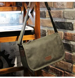 Detailed lifestyle view of the vintage green messenger crossbody bag hanging on a rustic wooden shelf.