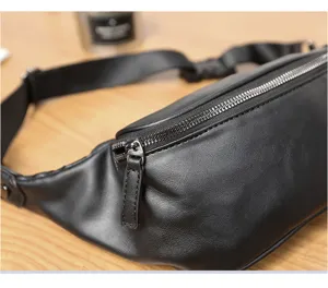 Close-up detail of the black leather chest bag showing the smooth zipper and texture.