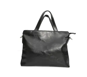 Primo piano della borsa da lavoro nera in pelle morbida con texture e manici ben visibili.