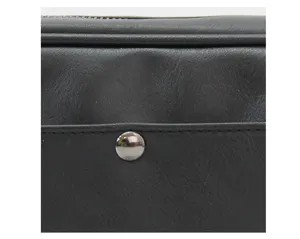 Detalle de bolso bandolera de cuero negro para hombre con cremallera metálica y cierre de botón.