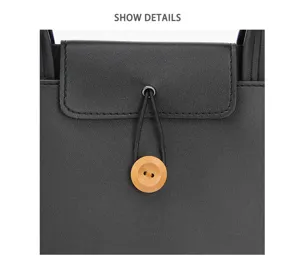 Black leather laptop bag detail close-up showing wooden button closure and dual handles.