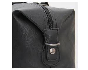 Close-up detail of black leather travel bag zipper and metal ring hardware accent.