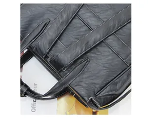 Detailed view of black leather travel bag with white stitching and durable shoulder straps.