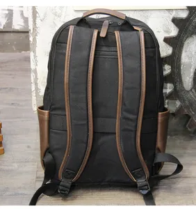Detailed view of the black canvas casual backpack with brown leather straps and practical storage.