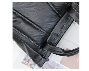 Gros plan détaillé d'un sac cabas en cuir synthétique noir avec des coutures blanches contrastées.