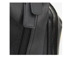 Close up view of black leather backpack detail, showing metal zippers and fine texture.