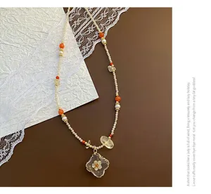 Gros plan détaillé de la texture du pendentif en résine et du collier de perles fin.