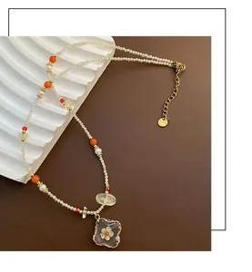 Collier perlé élégant avec pendentif en résine florale, bijou tendance pour femme moderne.
