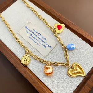 Gold titanium steel multi charm necklace with red heart pendant and vintage charms detail.