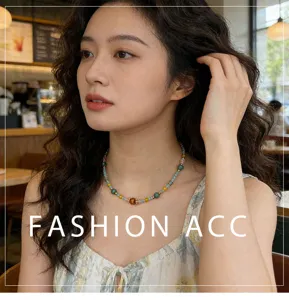 Gros plan sur le collier ras de cou en perles colorées porté par le modèle au café.