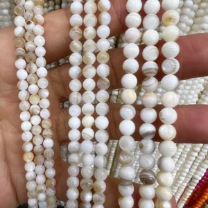Closeup detail of natural white freshwater shell round beads, smooth surface texture.