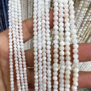 Close up view of white freshwater shell round beads strands, smooth surface and pearl luster texture.