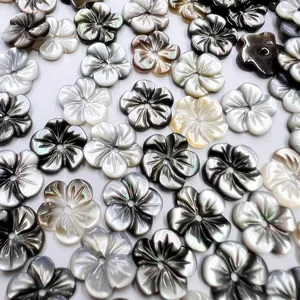 Close-up detail of carved mother-of-pearl shell flower beads for DIY jewelry making.