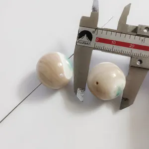 Close-up detail of natural green shell mother of pearl bead measured by tool for DIY craft.