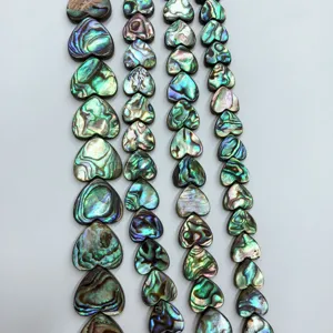 Gros plan de perles en coquille d'ormeau en forme de coeur, composants de bijoux colorés.