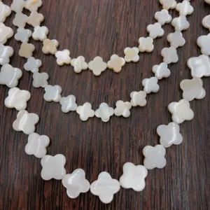 Close-up detail of white mother-of-pearl clover shell bead strands for DIY jewelry making.