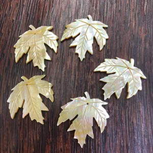 Close-up details of carved shell maple leaf pendant, showing natural mother-of-pearl texture.