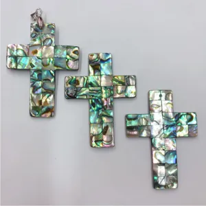Close-up of three colorful abalone shell cross pendants, shell mosaic DIY jewelry detail view.