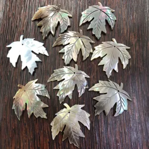 Detailed close-up of carved mother-of-pearl maple leaf pendants for DIY jewelry making.