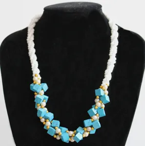 Chic multi-element beaded necklace with white twisted beads, turquoise cubes, and gold accents.