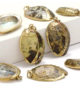 Close-up of natural green abalone shell pendants with gold-plated edges, jewelry making details.