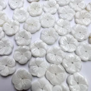 Detail closeup of white carved shell flower beads for DIY ancient jewelry and hair accessories.