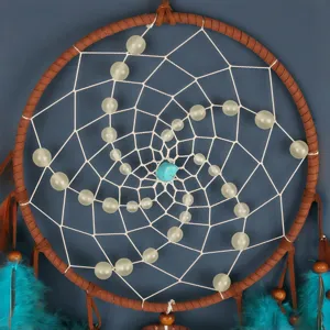 Detailweergave van handgemaakte dromenvanger met lichtgevende kralen en turkoois steen.