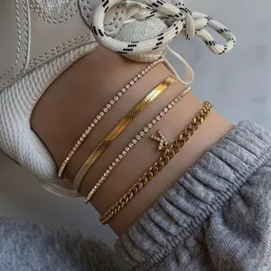 Set of 4 gold anklets featuring crystal tennis chains, sleek snake chain, and a letter K charm.