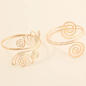 Stijlvolle gouden armbanden met gedetailleerde spiraalvormige en geometrische patronen.