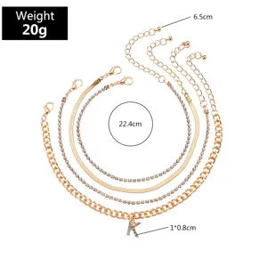 Detailed view of the 4-piece gold-tone layered anklet set with rhinestone letter K charm and size specs.