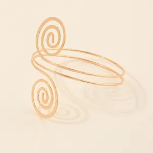 Gedetailleerd overzicht van de gouden metalen spiraal armband, geometrisch arm sieraad.