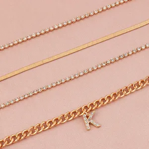 Set of four gold layered anklets with sparkling rhinestones and letter K pendant.
