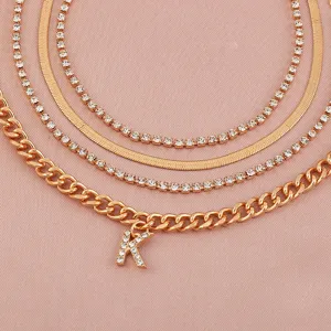 Detailed close-up of a multi-layer gold chain set featuring rhinestone and letter K charm.