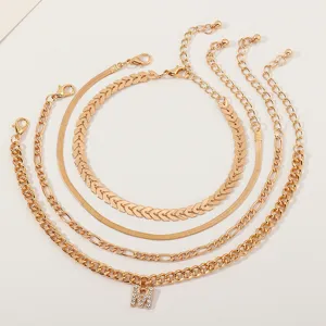 Set of 4 gold-tone metal anklets featuring a sparkling rhinestone letter M pendant.