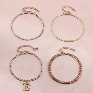 Detailed view of a 4-piece gold anklet set featuring rhinestone, snake, and letter charms.