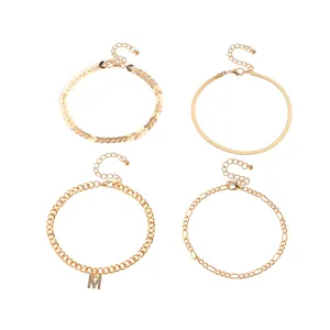 Gold anklet set detail featuring various chain links and a rhinestone letter pendant design.