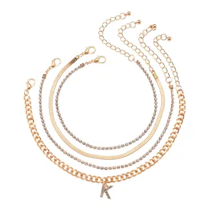 Layered gold anklet set with rhinestone letter K charm, trendy metal chain anklet for women.