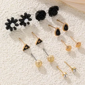 Elegantes Ohrring-Set in Schwarz und Gold mit Blumen und geometrischen Designs.