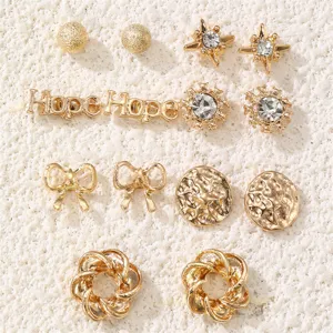 Detailansicht des goldenen Ohrring-Sets mit verschiedenen Stecker-Designs wie Sternen und Schleifen.
