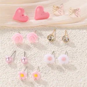 Detailansicht süßer Ohrring-Set-Details mit rosa Herzen, Schleifen und niedlichen Blumenmustern.