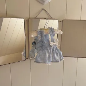 Vista detallada de vestido para mascotas a rayas azules y blancas con volantes y lazos.