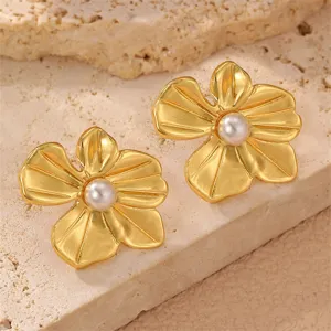 Nahaufnahme goldener Blumen-Ohrstecker mit Perle auf strukturiertem Steinhintergrund.