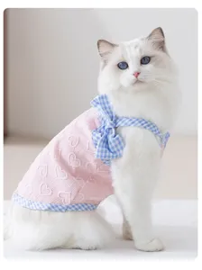 Detailaufnahme des niedlichen rosa herzgeprägten Haustierkleids mit blauem Karo-Schleifenband.