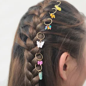 Detailansicht trendiger Gold-Haarringe mit bunten Perlen und Schmetterlingsanhängern.