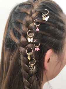 Nahaufnahme von geflochtenem Haar, verziert mit goldenen Schmetterlings- und Stern-Haarringen.