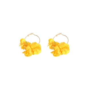 Nahaufnahme von gelben Stoffblumen-Creolen mit leuchtenden mehrschichtigen Blütenblättern.