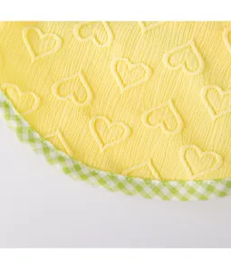 Nahaufnahme des gelben Haustierbekleidungsstoffs mit geprägten Herzen und kariertem Saum.