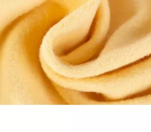 Close-up detail of soft yellow pet clothing fabric, showing cozy knit texture and warm tone.