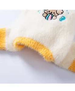 Detalle de ropa de forro polar para mascotas con bordado bonito y ribete amarillo.