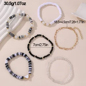 Set aus bunten Tonperlen und Metallketten Armbändern für Damen, filigrane handgemachte Schmuckdetails.